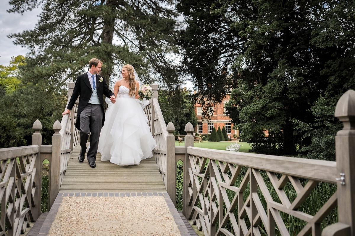 Fiona & James crossing the bridge to their romantic river island marquee setting